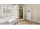 Bright bathroom featuring a soaking tub, tiled shower, and a white linen cabinet for storage at 330 Meadowcrest Cir, Canton, GA 30115