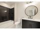 Modern bathroom with black tiled shower, sleek vanity with round mirror, and contemporary fixtures at 6055 Tattnall Overlook, Acworth, GA 30101