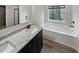Modern bathroom with double vanity, granite countertops, black hardware, soaking tub, and wood look floors at 4963 Arbor View Nw Pkwy, Acworth, GA 30101