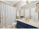 Elegant bathroom with a navy blue vanity, gold hardware, and a shower-tub combination with a decorative curtain at 10235 Worthington Mnr, Suwanee, GA 30024