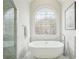 Elegant bathroom featuring a soaking tub and decorative window in natural light at 10235 Worthington Mnr, Suwanee, GA 30024