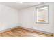 An empty bedroom with hardwood floors, white walls, a window, and grey trim at 1055 Ormewood Se Ave, Atlanta, GA 30316