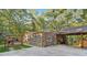 View of the stone exterior with car port and hot tub surrounded by lush green trees at 80 Rountree Rd, Riverdale, GA 30274