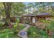 Charming stone cottage with lush front yard, stone walkway, and mature trees, offering a peaceful setting at 80 Rountree Rd, Riverdale, GA 30274
