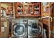 Laundry room with modern washer and dryer, wooden cabinets, and brick accent wall, a functional space at 80 Rountree Rd, Riverdale, GA 30274