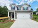 Two-story home featuring a brick and vinyl facade, a two-car garage, and a well-manicured front lawn at 145 Scarlett Place Dr, Bowdon, GA 30108