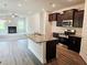 Modern kitchen and living room featuring granite countertops, stainless steel appliances, and dark cabinetry at 145 Scarlett Place Dr, Bowdon, GA 30108
