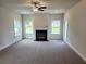Spacious living room featuring a fireplace, large windows, ceiling fan, and plush carpeting at 145 Scarlett Place Dr, Bowdon, GA 30108