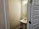 A simple half bathroom with a pedestal sink and a round mirror with a paint grade door and trim at 145 Scarlett Place Dr, Bowdon, GA 30108