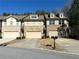 A view of townhomes showing the garages, driveways, and mailboxes on a sunny day at 3275 Wild Basil Ln, Buford, GA 30519