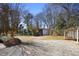 View of the spacious backyard with gravel area, mature trees, and outbuildings for storage at 5812 Dogwood Cir, Austell, GA 30168