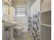 Clean bathroom featuring a pedestal sink, toilet, and a shower with blue floral curtains at 5812 Dogwood Cir, Austell, GA 30168