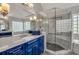 Elegant bathroom featuring a glass shower, marble countertop, blue cabinets, and a large mirror at 1129 Gavinwood Pl, Decatur, GA 30033
