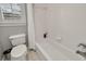 Clean white bathroom featuring a tub with white tiled walls and a toilet near a window with shutters at 1129 Gavinwood Pl, Decatur, GA 30033