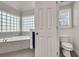 Bathroom with tub encased in marble with glass block window and a separate toilet room at 1129 Gavinwood Pl, Decatur, GA 30033