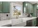 Bright kitchen featuring a white farmhouse sink, stainless dishwasher, and green cabinetry, with a view to the outside at 151 Wilbur Ln, Lawrenceville, GA 30044