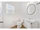 Simple half-bathroom featuring a pedestal sink, toilet, and a round mirror at 28 Dover Commons Dr, Tucker, GA 30084