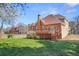 Large grassy backyard with a deck and a brown house with a chimney at 540 Clubfield Drive, Roswell, GA 30075