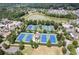 Aerial view featuring community tennis courts near homes and surrounded by trees and a pond at 7315 Cordery Rd, Cumming, GA 30040