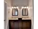 Elegant bathroom featuring double vanities with dark wood cabinets, granite counters, and modern lighting at 1541 Towne Park Ct, Lawrenceville, GA 30044