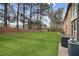View of a backyard with green lawn, fence, mature trees and air conditioning units at 1605 Beaumont Cir, Duluth, GA 30096