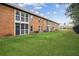 View of a brick townhome building with a well-manicured lawn and mature trees on a sunny day at 1605 Beaumont Cir, Duluth, GA 30096