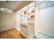 Bright walk-in closet featuring custom shelves, drawers, hardwood floors, and a stylish chandelier at 2179 Marann Ne Dr, Atlanta, GA 30345