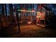 Backyard wooden playset featuring swings, slide, and playhouse illuminated with festive lighting for nighttime fun at 1072 Powell Wright Rd, Marietta, GA 30066