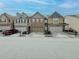 View of a row of townhomes, each with unique architectural details and individual garages at 3318 Sardis Bend Dr, Buford, GA 30519