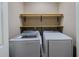 Neat laundry room with white washer and dryer, complemented by wood shelves for optimal storage and organization at 3318 Sardis Bend Dr, Buford, GA 30519