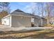 Back exterior view of a home with neutral colored siding, a deck, and a three-car garage at 6010 Canaan Woods Dr, South Fulton, GA 30331