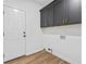 Well-lit laundry room featuring dark cabinets, a white door, and light wood-look flooring at 6010 Canaan Woods Dr, South Fulton, GA 30331