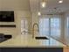 Kitchen island with quartz countertop, modern faucet, pendant lights, and a view to the outdoor deck at 1305 Country Acres Ln, Lawrenceville, GA 30045