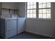 Laundry room with washer, dryer, shelving, natural light from a large window, and gray tile at 1305 Country Acres Ln, Lawrenceville, GA 30045