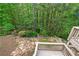 Elevated view of the stone patio and wooded backyard, complete with lush landscaping and mature trees at 994 Fairview Club Cir, Dacula, GA 30019