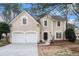Charming two-story home with a two-car garage, neutral stucco exterior, and landscaped front yard with mature trees at 725 Victoria Station Blvd, Lawrenceville, GA 30043