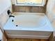 A white bathtub with tile surround and dark hardware sits below a window at 15 Blanket Pass, Covington, GA 30016