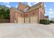 Three-car garage with neutral colored doors and spacious driveway, plus brick exterior at 2571 Weddington Ne Rdg, Marietta, GA 30068