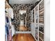 Walk-in closet featuring clothing racks, glass-fronted shelves, and black and white wallpaper at 2571 Weddington Ne Rdg, Marietta, GA 30068