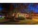 Charming single-story brick home with a manicured lawn and mature trees at dusk at 1408 Aramore Dr, Conyers, GA 30013