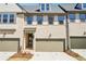 Townhome exterior with two-car garage, light brick facade, covered entry, and landscaped front yard at 3900 Allegretto Cir # 51, Atlanta, GA 30339
