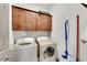 Efficient laundry room with modern washer and dryer, cabinet storage, and cleaning supplies at 2318 Willington Shoals Se Pl, Smyrna, GA 30080