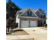 Charming two-story home with a two-car garage and gray and brick exterior on a sunny day at 3831 Village Crossing Ln, Ellenwood, GA 30294