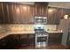 A stylish kitchen with dark wood cabinets, granite countertops, and modern stainless steel appliances at 3831 Village Crossing Ln, Ellenwood, GA 30294