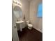 Well lit powder room with pedestal sink and a decorative oval mirror, complemented by dark wood floors at 3831 Village Crossing Ln, Ellenwood, GA 30294