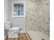 Bathroom with a marble tiled walk-in shower, toilet, and a window at 4647 Wonder Valley Trl, Decatur, GA 30034