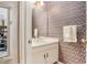 Cozy powder room featuring a pedestal sink and patterned wallpaper at 4484 Hunters Way, Stone Mountain, GA 30083