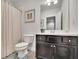 Cozy bathroom featuring a dark vanity with white countertop, framed mirror, and shower with striped curtain at 318 Lantana Ln, Woodstock, GA 30188