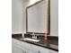 Bathroom vanity with dark countertop, white cabinets, chrome faucet, and framed mirror at 318 Lantana Ln, Woodstock, GA 30188