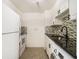 Galley kitchen with black countertops, white appliances, and a modern, decorative backsplash at 375 Ralph Mcgill Ne Blvd # 804, Atlanta, GA 30312